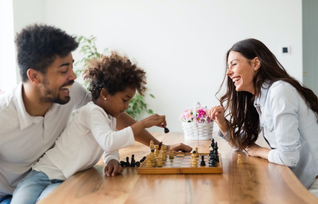 Glückliche Familie, die zu Hause zusammen Schach spielt