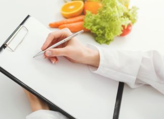 Nutritionist doctor writing diet plan on table