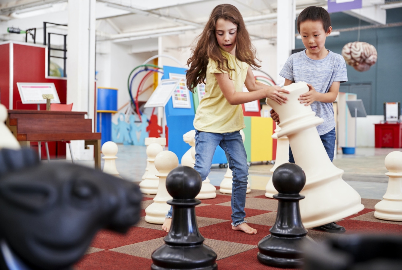 Two children playing giant chess at a science centre